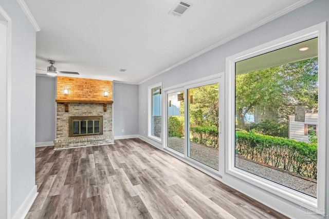 unfurnished living room featuring crown molding, hardwood / wood-style floors, ceiling fan, and a brick fireplace