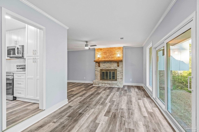 unfurnished living room featuring a fireplace, light hardwood / wood-style flooring, ceiling fan, and ornamental molding