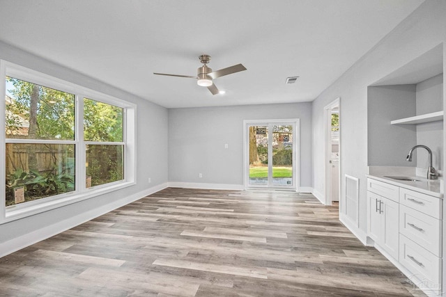 unfurnished dining area with ceiling fan, light wood-type flooring, and sink