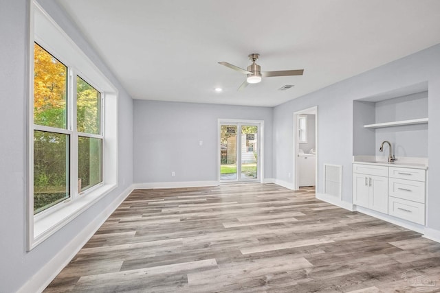 interior space featuring washer / dryer, light wood-type flooring, ceiling fan, and sink