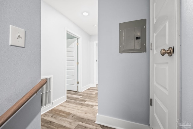 hallway featuring electric panel and light hardwood / wood-style floors