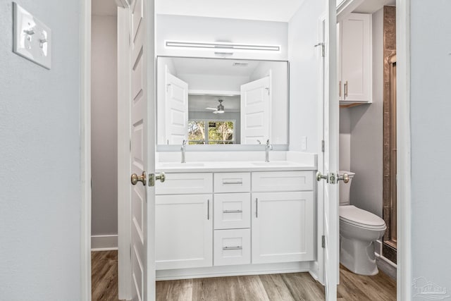 bathroom with wood-type flooring, vanity, toilet, and ceiling fan