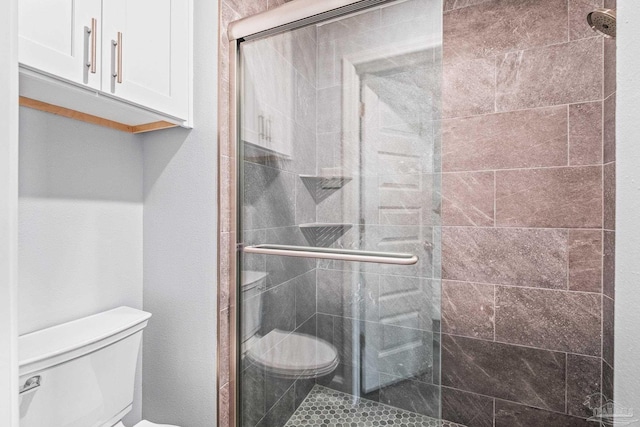 bathroom with toilet and a shower with shower door