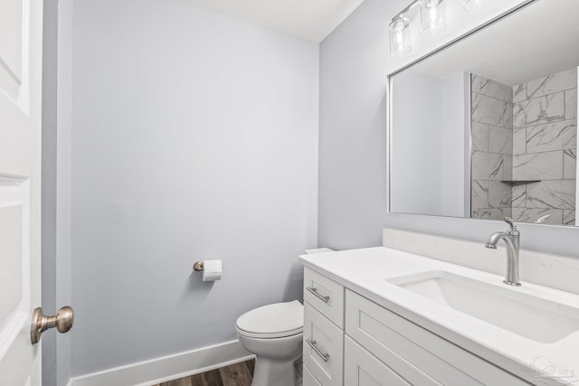 bathroom with hardwood / wood-style floors, vanity, a tile shower, and toilet