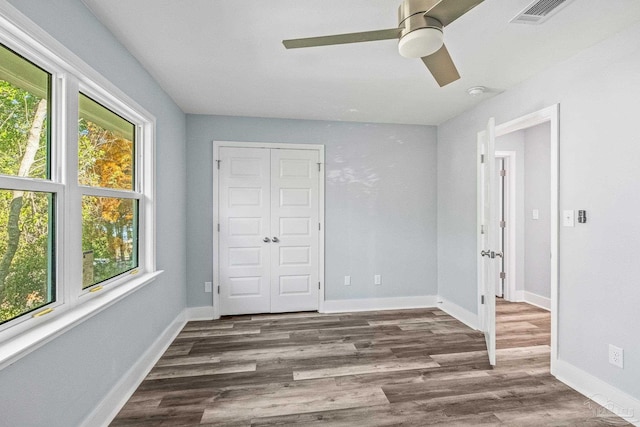 unfurnished bedroom featuring ceiling fan, dark wood-type flooring, and a closet