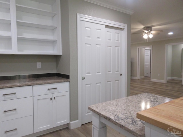 kitchen featuring ceiling fan, white cabinetry, light wood-type flooring, crown molding, and butcher block counters