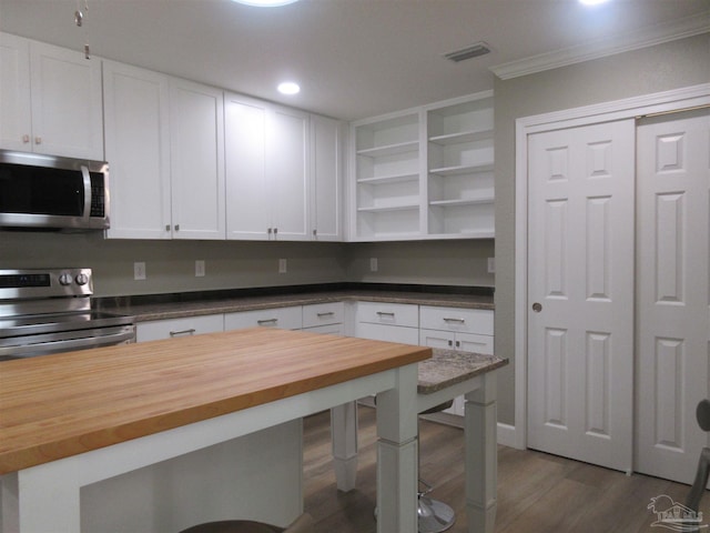 kitchen featuring white cabinetry, dark hardwood / wood-style flooring, stainless steel appliances, wooden counters, and ornamental molding