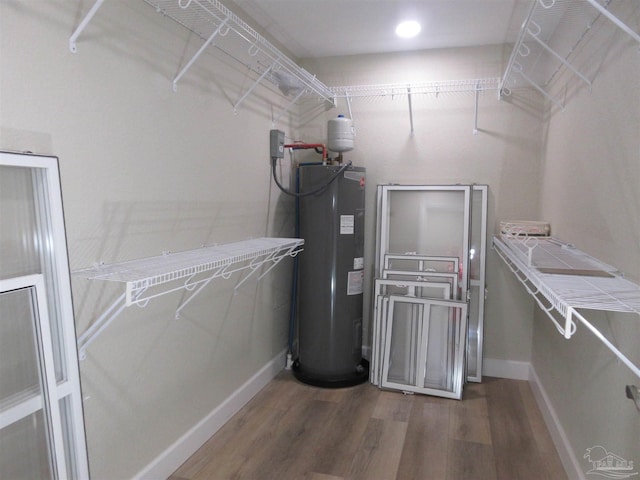 spacious closet featuring water heater and dark hardwood / wood-style flooring