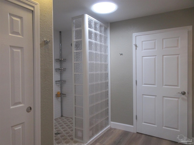 bathroom with a tile shower and hardwood / wood-style flooring