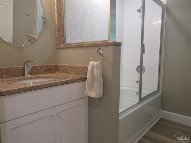 bathroom featuring enclosed tub / shower combo, vanity, and hardwood / wood-style floors