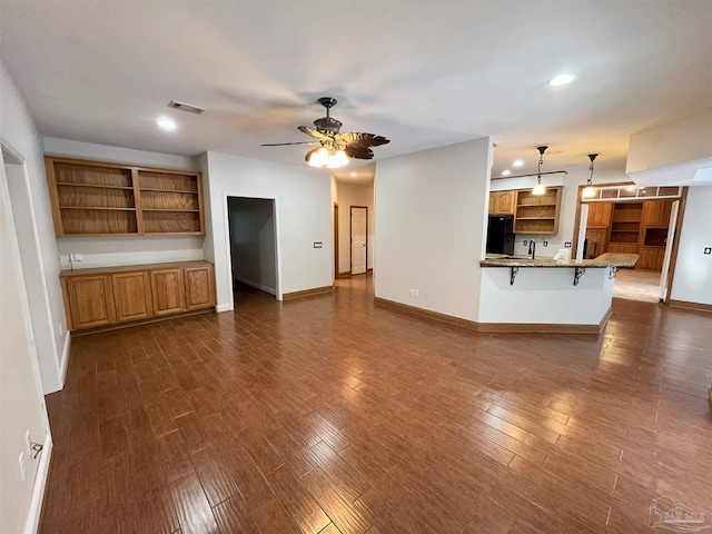 unfurnished living room featuring ceiling fan, sink, and dark wood-type flooring