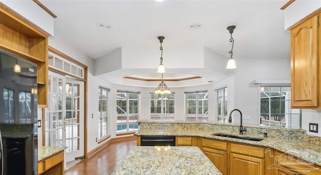 kitchen featuring light stone counters, sink, black appliances, and decorative light fixtures