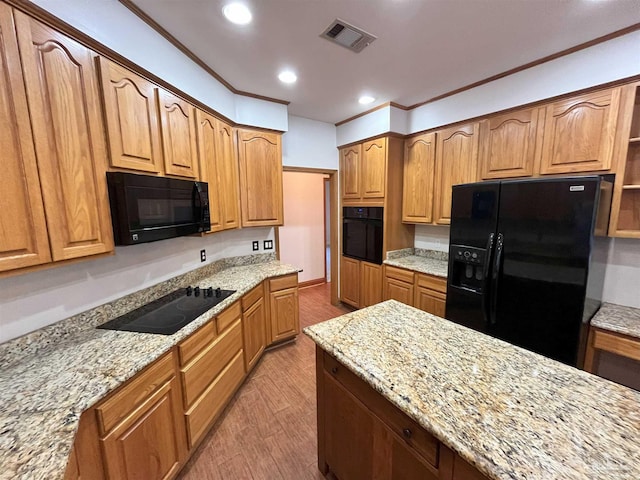 kitchen featuring light stone countertops, light wood-type flooring, crown molding, and black appliances