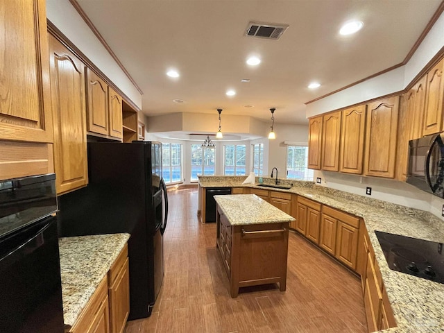 kitchen featuring a center island, sink, decorative light fixtures, black appliances, and hardwood / wood-style flooring