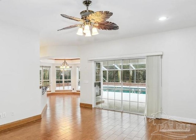 interior space with ceiling fan with notable chandelier and hardwood / wood-style flooring