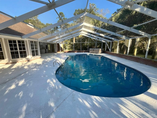 view of pool featuring a hot tub, glass enclosure, and a patio area