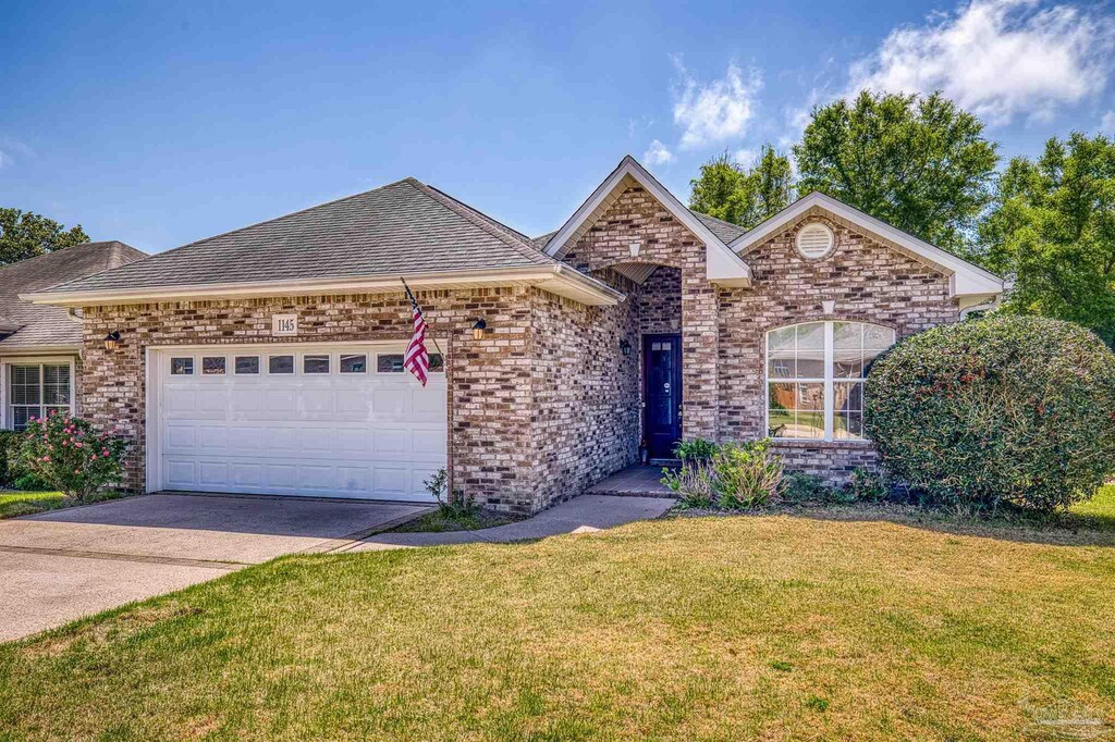 single story home featuring an attached garage, a front yard, brick siding, roof with shingles, and driveway