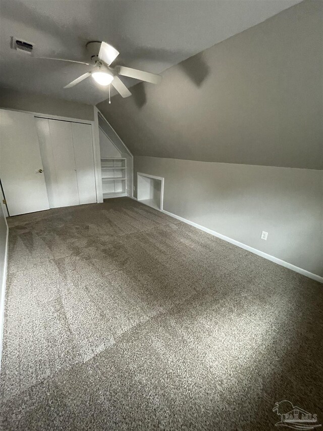 additional living space with ceiling fan, built in features, vaulted ceiling, carpet, and baseboards
