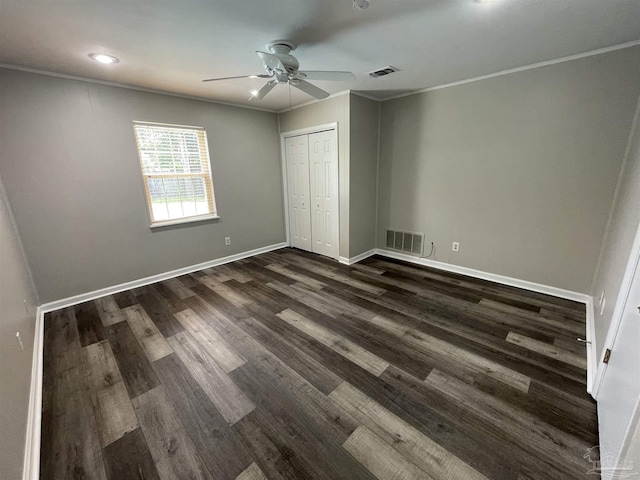 unfurnished bedroom featuring dark wood-style flooring, baseboards, ornamental molding, ceiling fan, and a closet