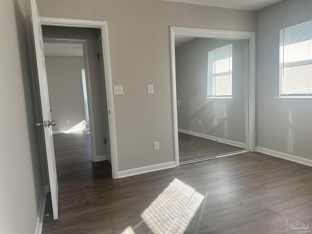 unfurnished bedroom with a closet and dark hardwood / wood-style flooring