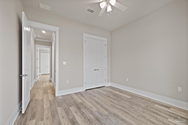 unfurnished bedroom with ceiling fan, light wood-type flooring, and a closet