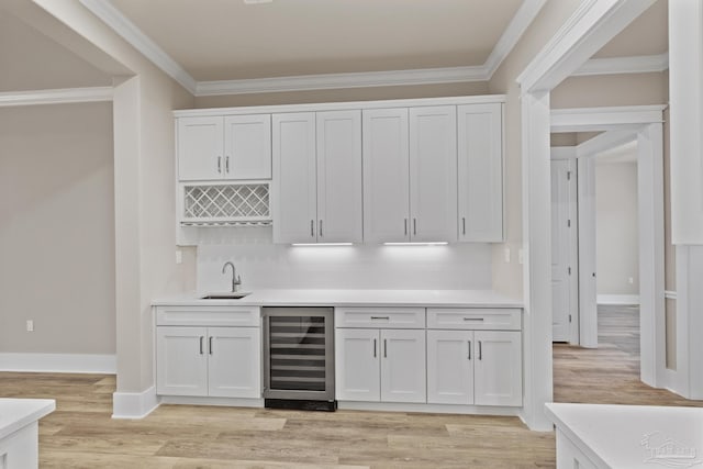 bar featuring white cabinets, crown molding, sink, and beverage cooler