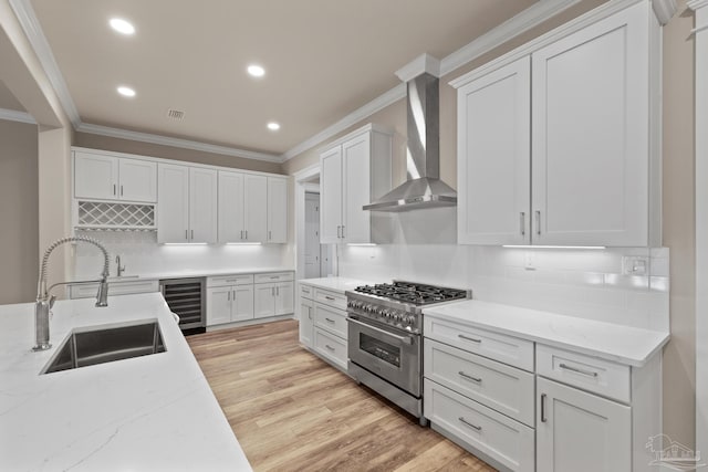 kitchen featuring white cabinetry, stainless steel range, wall chimney exhaust hood, and sink