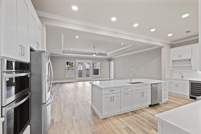 kitchen featuring sink, appliances with stainless steel finishes, white cabinetry, wine cooler, and a raised ceiling