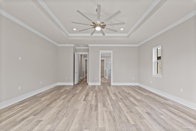 unfurnished room with crown molding, a raised ceiling, ceiling fan, and light wood-type flooring