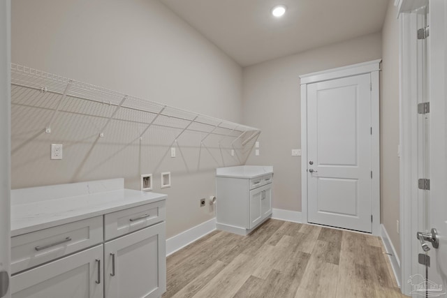 laundry area featuring cabinets, washer hookup, and light hardwood / wood-style floors