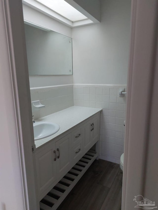 bathroom featuring tile walls, vanity, hardwood / wood-style flooring, and toilet