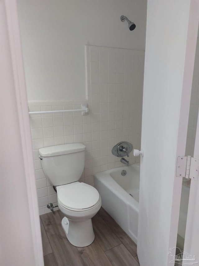 bathroom featuring tile walls, tiled shower / bath combo, and toilet