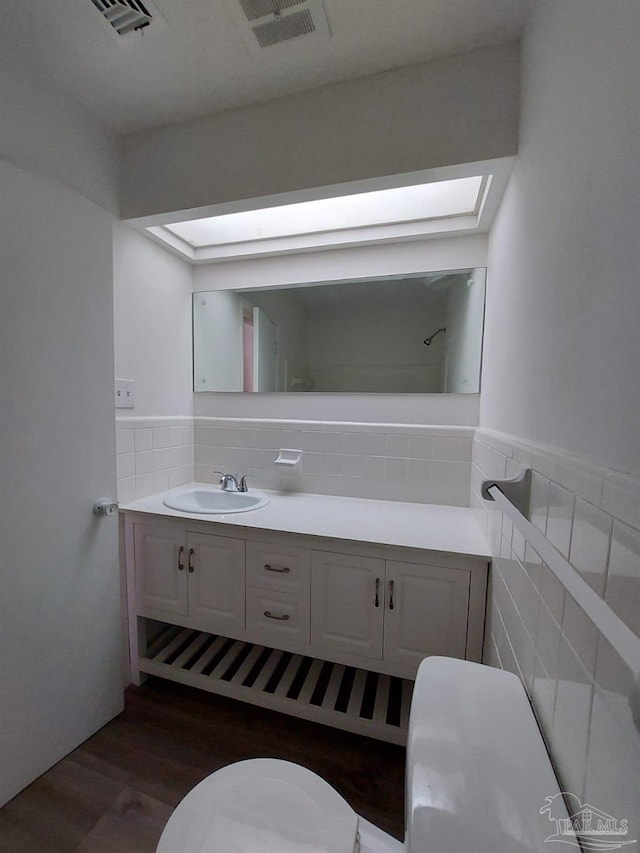 bathroom with tile walls, vanity, hardwood / wood-style floors, and toilet