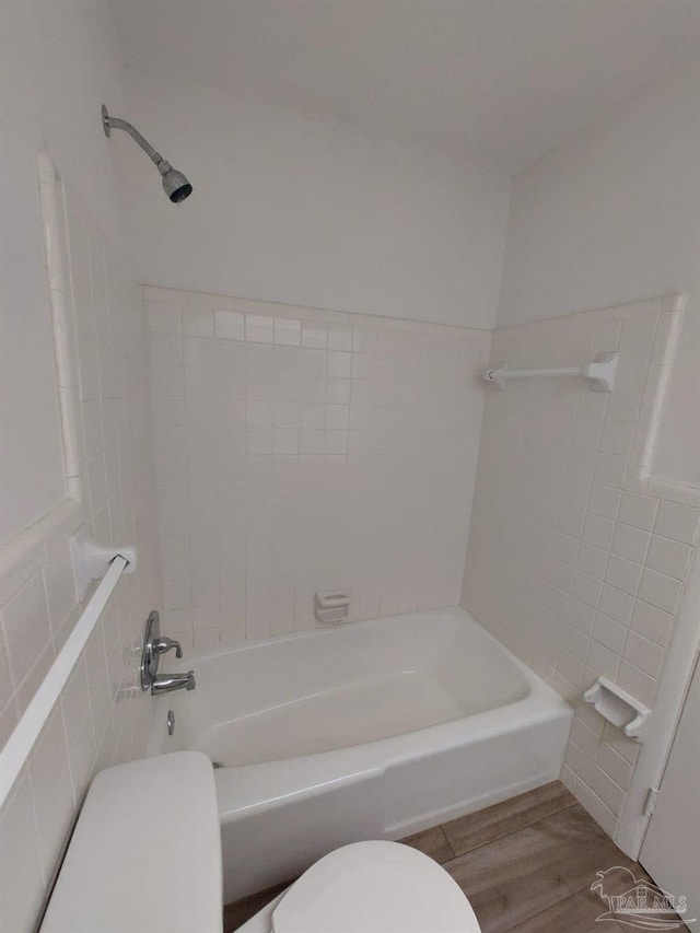 bathroom featuring hardwood / wood-style flooring, tiled shower / bath, and toilet