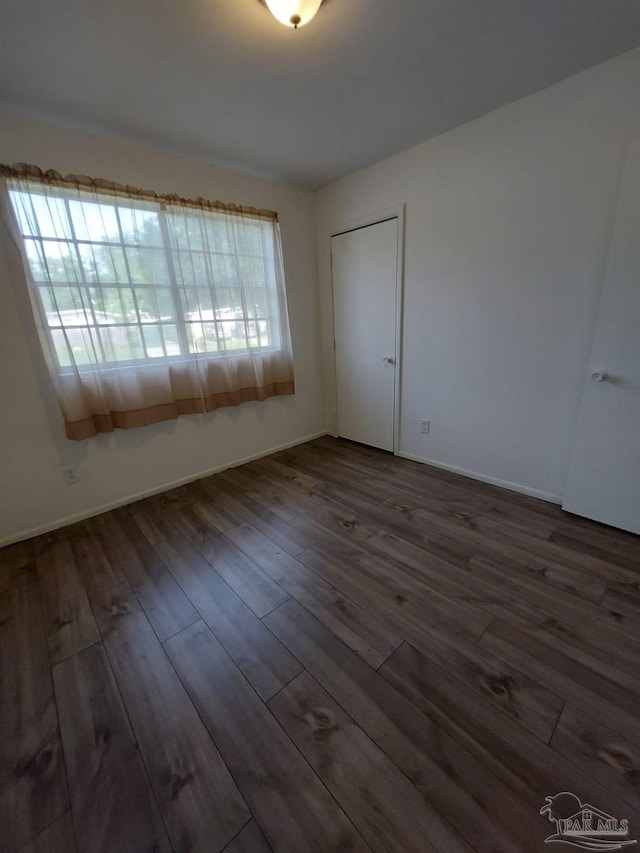 unfurnished room featuring dark hardwood / wood-style flooring and a healthy amount of sunlight