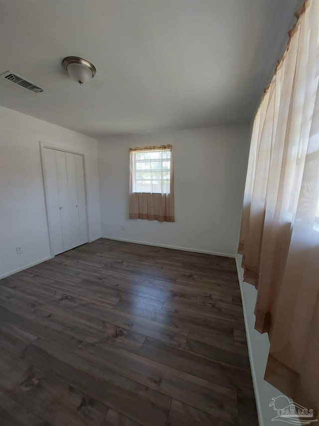 unfurnished bedroom with dark wood-type flooring and a closet