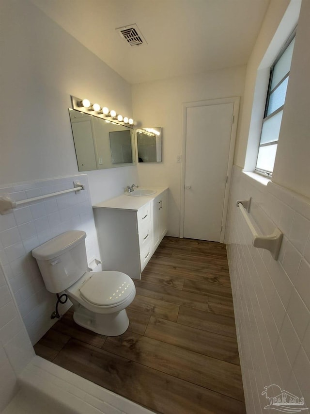 bathroom featuring vanity, toilet, and tile walls