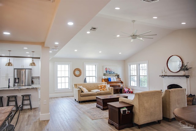 living room with vaulted ceiling, light hardwood / wood-style flooring, plenty of natural light, and a fireplace