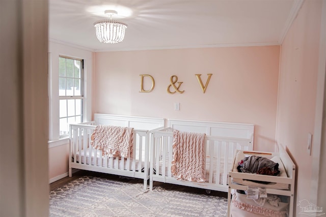 bedroom featuring crown molding, hardwood / wood-style floors, a chandelier, and a nursery area