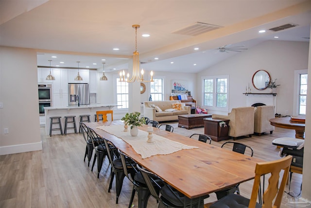 dining room featuring light wood-type flooring, ceiling fan with notable chandelier, and lofted ceiling