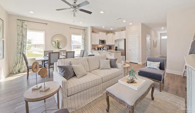 living room with light hardwood / wood-style floors and ceiling fan