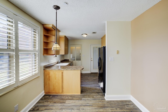 2007 E Gadsden St Unit 102, Pensacola, FL 32501 - kitchen with open shelves, a textured ceiling, dark wood finished floors, freestanding refrigerator, and a peninsula