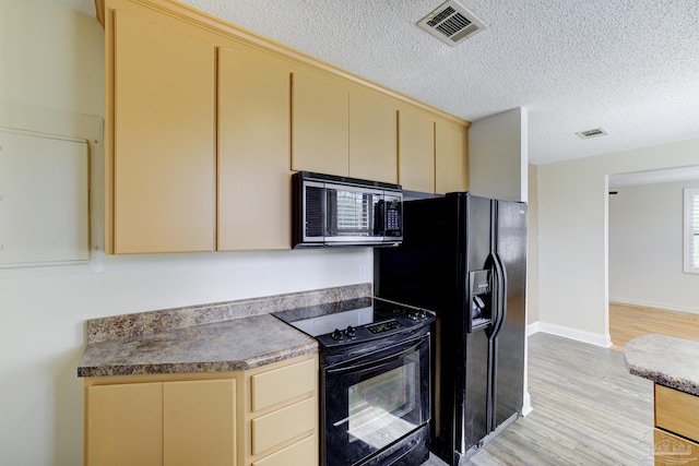 2007 E Gadsden St Unit 102, Pensacola, FL 32501 - kitchen with black appliances, cream cabinets, light wood finished floors, a textured ceiling, and baseboards