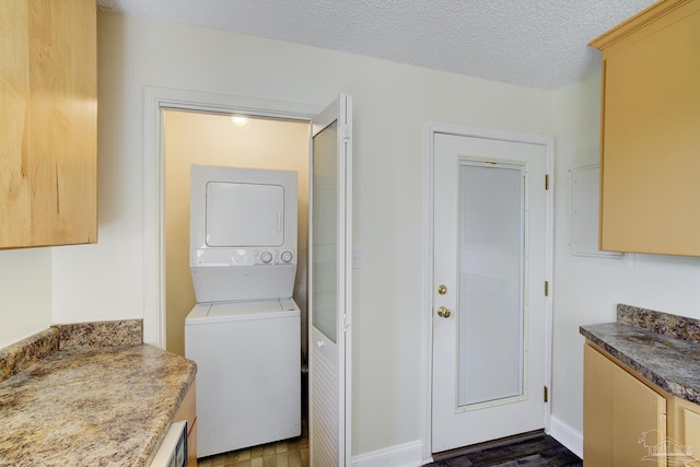 2007 E Gadsden St Unit 102, Pensacola, FL 32501 - washroom featuring stacked washer and clothes dryer, a textured ceiling, dark wood finished floors, and baseboards