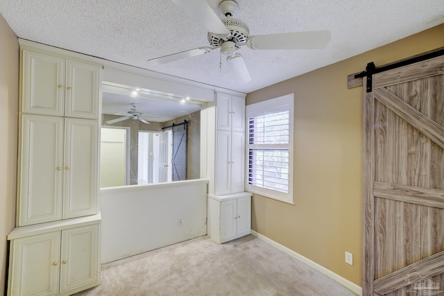 2007 E Gadsden St Unit 102, Pensacola, FL 32501 - unfurnished bedroom with a barn door, light colored carpet, a textured ceiling, ceiling fan, and baseboards
