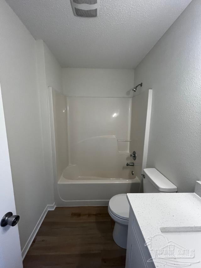 1984 Hillary Thompson Rd, Milton, FL 32570 - full bath featuring toilet, wood finished floors, vanity, a textured ceiling, and shower / washtub combination
