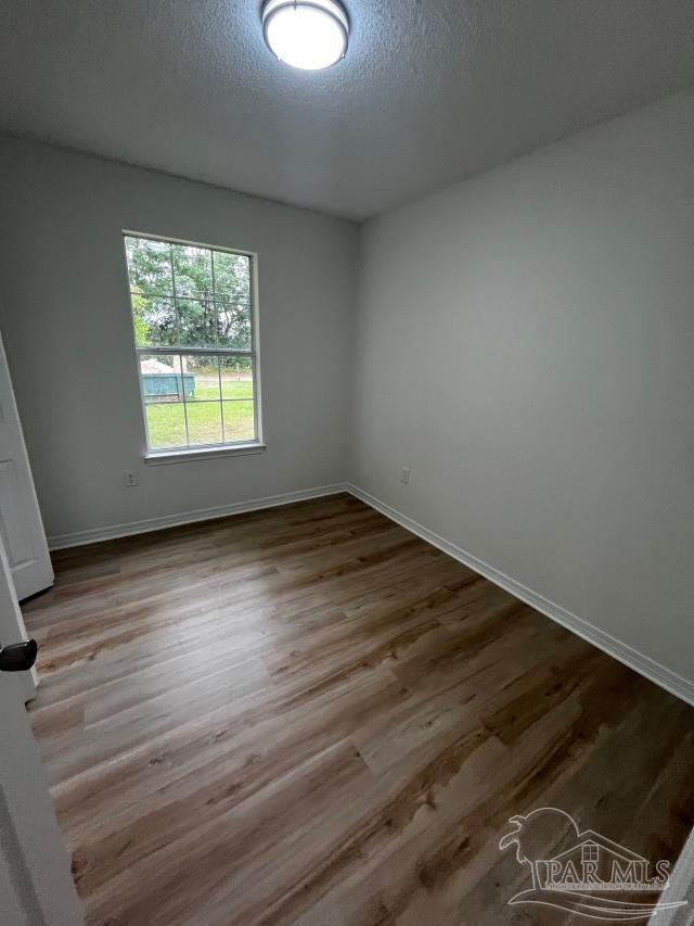 1984 Hillary Thompson Rd, Milton, FL 32570 - unfurnished room featuring wood finished floors, baseboards, and a textured ceiling