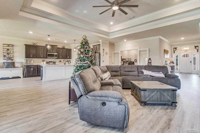 living room featuring a tray ceiling, ceiling fan, light hardwood / wood-style flooring, and ornamental molding