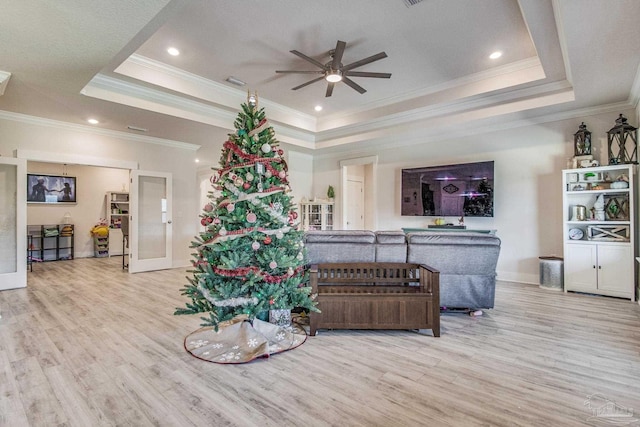 living room featuring a raised ceiling, light hardwood / wood-style floors, and ornamental molding