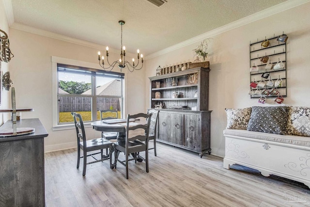 dining area with a chandelier, a textured ceiling, light hardwood / wood-style flooring, and crown molding